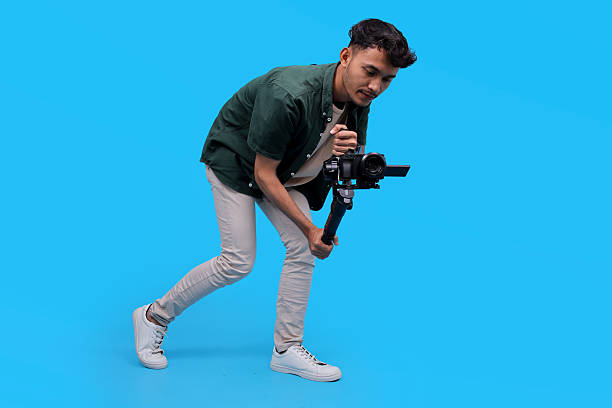 istock Young Male Videographer Filming With A Camera On A Gimbal, Crouching Down To Get A Low Angle Shot 2235861563