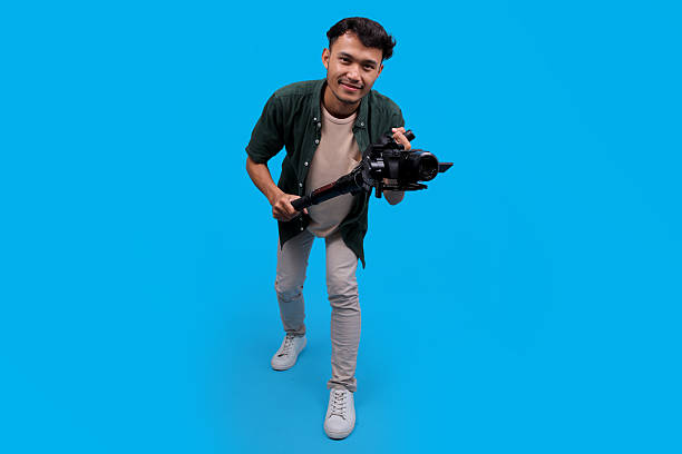 istock Happy Young Videographer Man Smiling While Holding A Camera On A Gimbal Stabilizer 2235861567