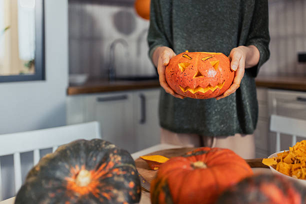 istock Carved Halloween Pumpkin Held by Hands in a Cozy Kitchen Scene 2235862530