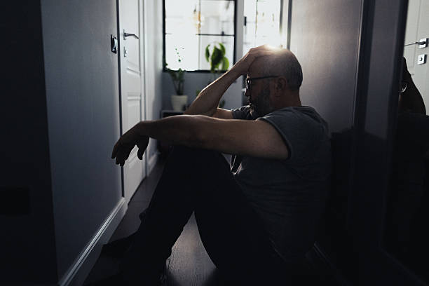 istock Silhouette of a Sad Man Sitting Alone in a Dark Hallway 2235862770