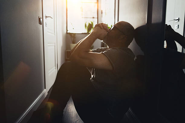 istock Silhouette of a Sad Man Sitting Alone in a Dark Hallway 2235862776