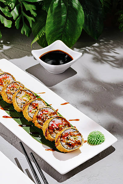 Sushi rolls on a plate with dipping sauce and garnishes in a garden setting
