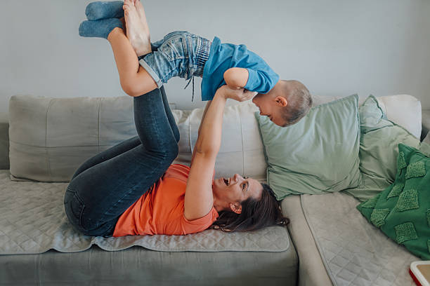istock Mother lying on sofa lifting son in the air and playing 2235863891