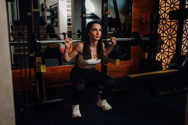 istock Determined sportswoman performing squats with barbell in modern gym 2235865796