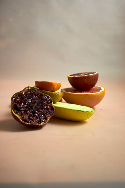 Creative food composition with grapefruit, kiwi, pomegranate, chili pepper, and zucchini arranged in artistic still life on pastel background. Modern minimal style for healthy eating concepts