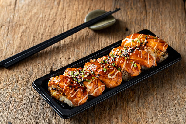 istock Delicious Salmon Sushi with Drizzled Sauce on Rustic Wooden Table 2235871888