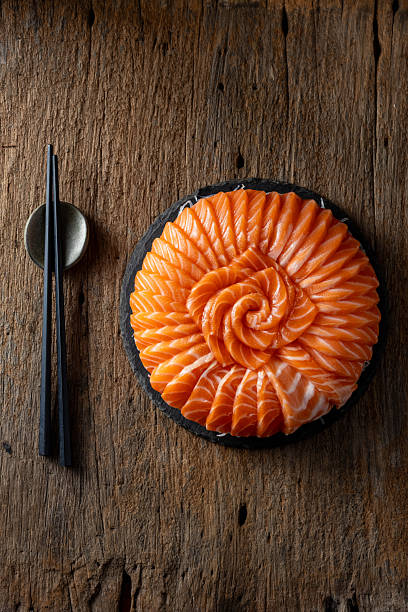 istock Fresh Salmon Slices Artfully Arranged on Black Plate with Chopsticks 2235872108