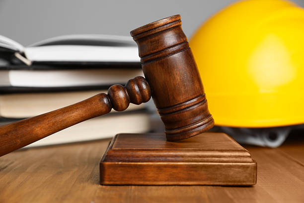 istock Accident at work concept. Gavel, books and construction worker's protective gear on wooden table, selective focus 2235872247