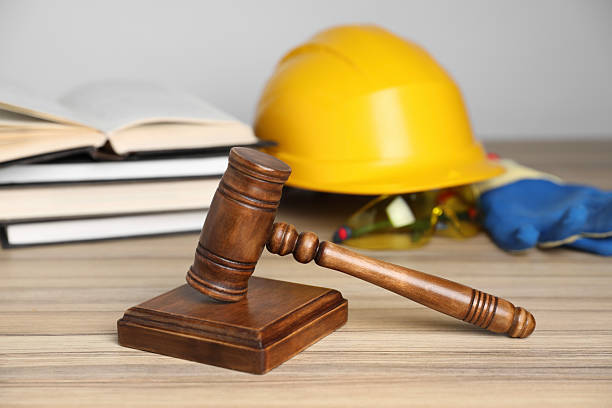 istock Accident at work concept. Gavel, books and construction worker's protective gear on wooden table, selective focus 2235872296