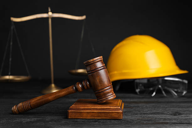 istock Accident at work concept. Gavel, scales and construction worker's protective gear on black wooden table, selective focus 2235872317