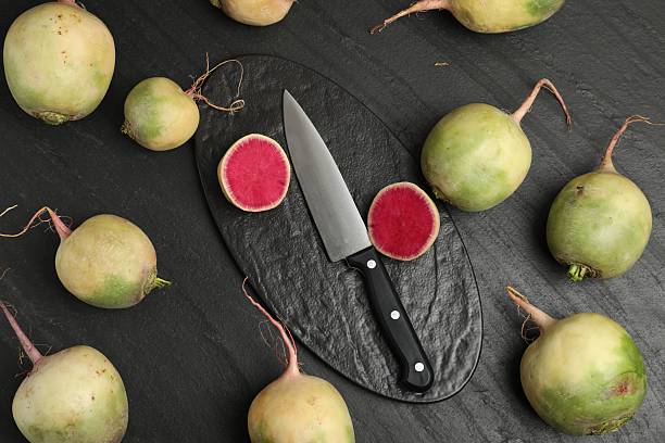 Fresh turnips and knife on black table, flat lay
