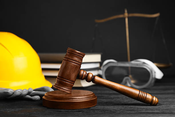 istock Accident at work concept. Gavel, books, scales and construction worker's protective gear on black wooden table, selective focus 2235872940