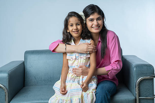 istock Happy mother with daughter sitting on sofa against white background 2235876772