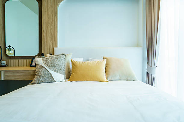 istock Modern bedroom with tidy bed, pillows, and duvet under natural sunlight. 2235877039