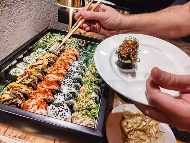istock Man taking tasty sushi roll from set at table 2235879396