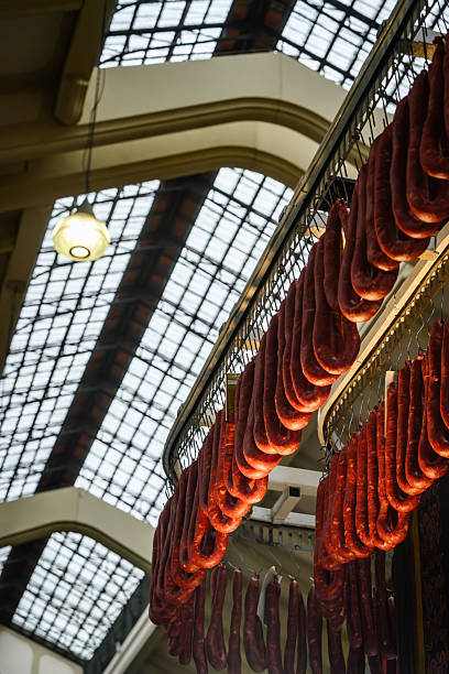 Hanging cured sausages displayed in a historic market hall setting