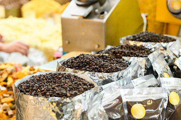Texture-rich close-up of evenly roasted coffee beans in containers at a market, showcasing their dark brown hues and glossy surfaces. Ideal for illustrating food, beverages, and coffee-related themes, this image captures the essence of freshly roasted coffee beans, exuding a sense of warmth and inviting aroma, perfect for showcasing in café promotions and culinary presentations.