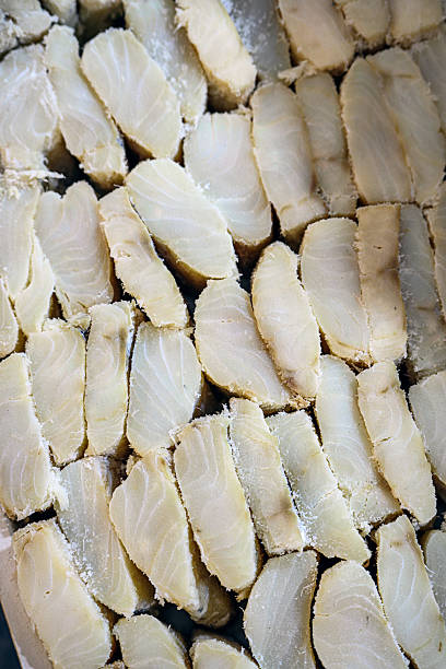 Rows of freshly cut salted fish slices are meticulously arranged on display, showcasing the texture and variety essential to traditional fish preservation. The photograph emphasizes the authenticity and craftsmanship involved in preparing these seafood delicacies, as seen often in classic markets.