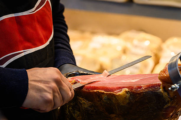 istock Slicing cured ham professionally with precision at a gourmet food stall 2235880584