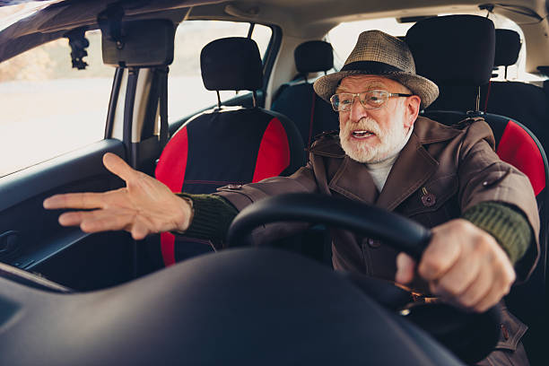 istock Elderly man in a classic coat driving a car and expressing animated emotions while engaged in a dynamic conversation 2235880675