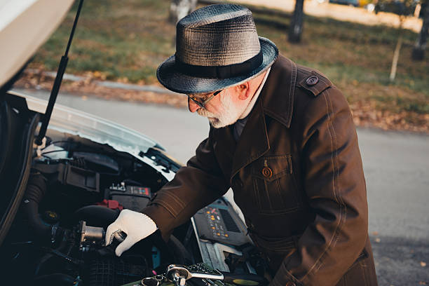 istock Elderly man inspecting car engine during a sunny autumn day outdoors in a park surrounded by peaceful nature 2235880702
