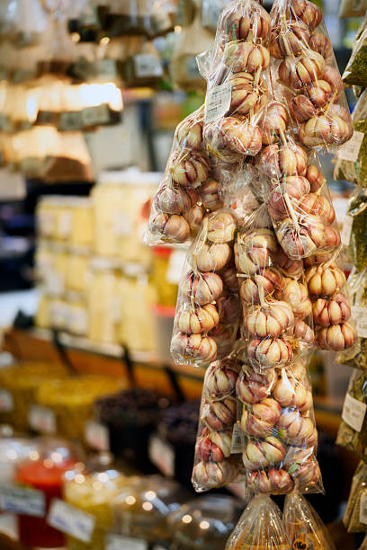 Bunches of garlic in clear packaging at a vibrant spice market stall