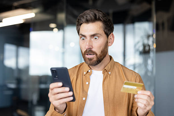 istock A surprised man reacts to his phone while holding a credit card 2235882712