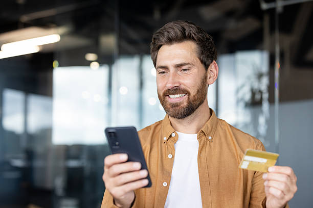 istock Happy businessman making online payment using smartphone and credit card 2235882715