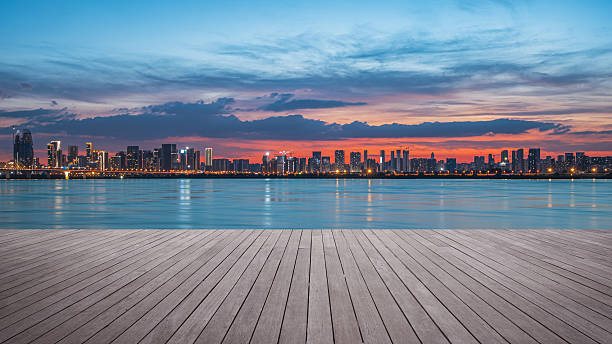 istock Empty wooden platform and modern urban waterfront skyline with dramatic sky and clouds during sunset 2235882930