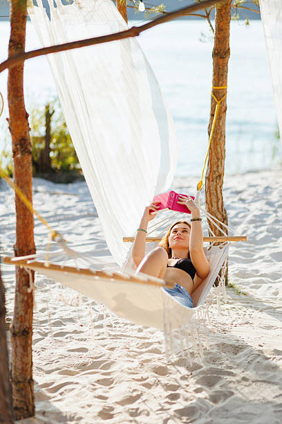 istock Relaxing Woman Reading a Book on a Hammock at a Sandy Beach 2235885568