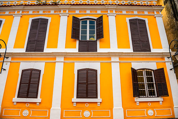 A street windows of an old building in Kuala Lumpur. Yellow wooden windows with white walls.