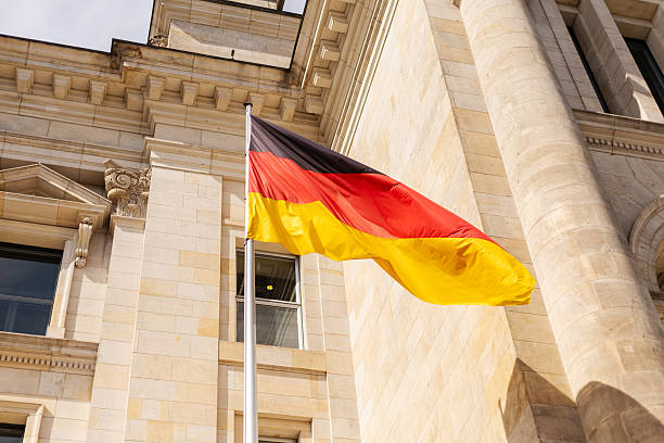 istock A vibrant German flag flutters against a clear blue sky, displaying its black, red, and gold colors. This scene captures the pride of Germany outside a prominent historic structure in Berlin 2235887346