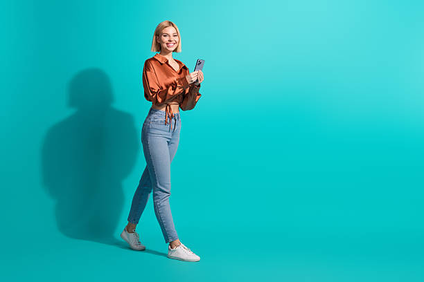 istock Charming young woman in casual outfit using smartphone against turquoise backdrop promoting a stylish and happy lifestyle 2235889637