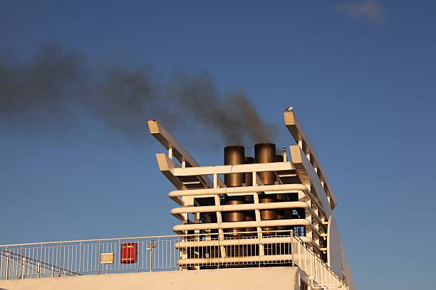 Black exhaust fumes smoke from a ferry chimney in Denmark. Air pollution from maritime transportation.