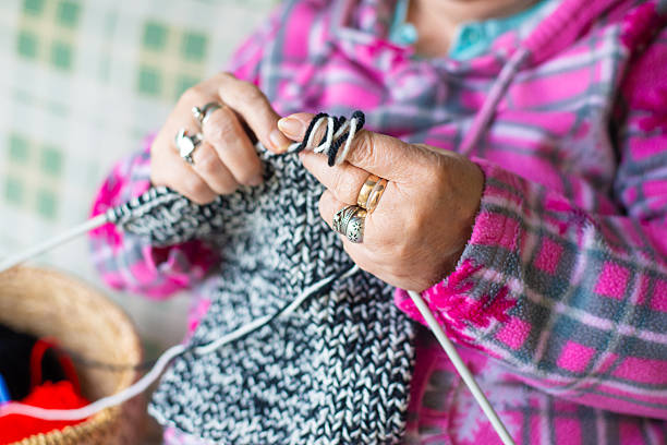 Senior woman knitting in the back yard while sitting in the porch swing in spring.