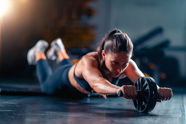 istock Using an ab weel for strength training in the gym, a woman improves power and streinght abs. 2235895290