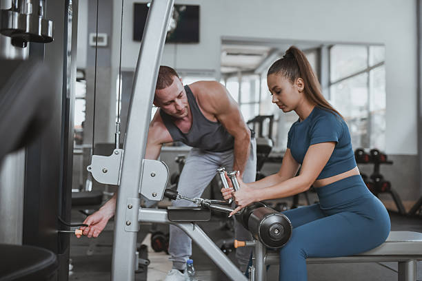istock Fitness Coach Guiding Female Athlete While Adjusting Weights On Lat Pulldown Machine In Gym 2235895397