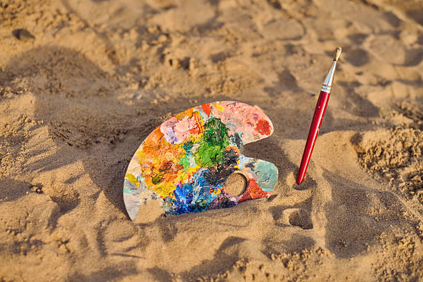 istock Colorful artist palette and brush on sandy beach 2235895742