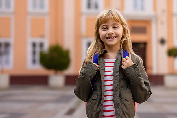 Cute little schoolgirl with school bag on a street. Back to study.