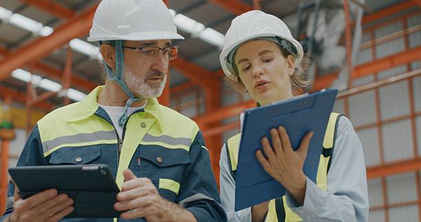 istock Male and female engineers with tablet and folder walking in warehouse 2235898977