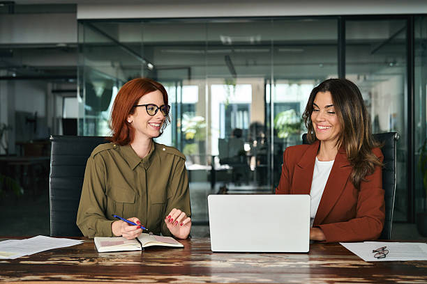 istock Two happy female coworkers working together using computer at desk in office. 2235900865