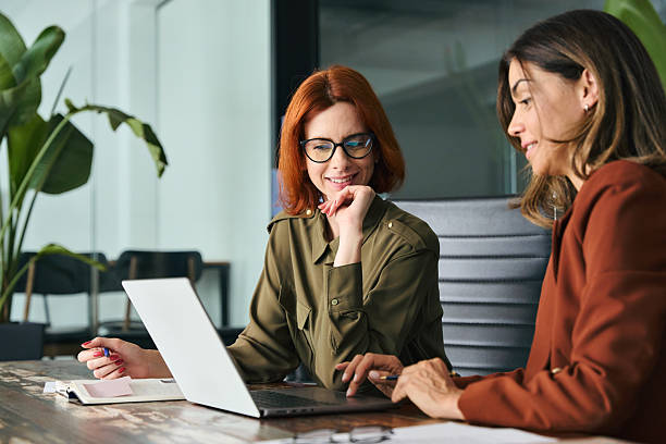 istock Two happy busy diverse women working together using computer at desk in office. 2235900869