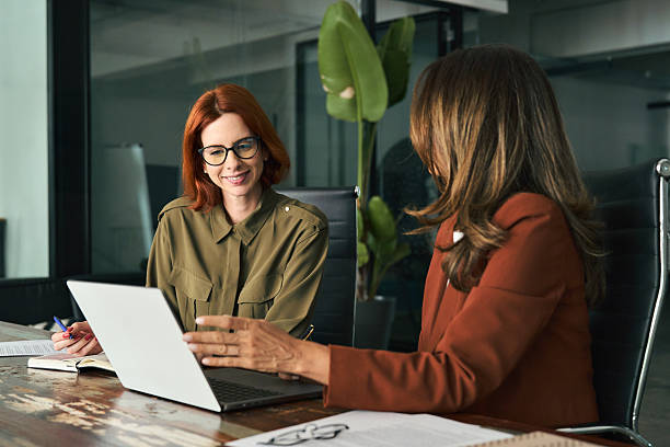 istock Two happy female coworkers working together using computer at desk in office. 2235900873