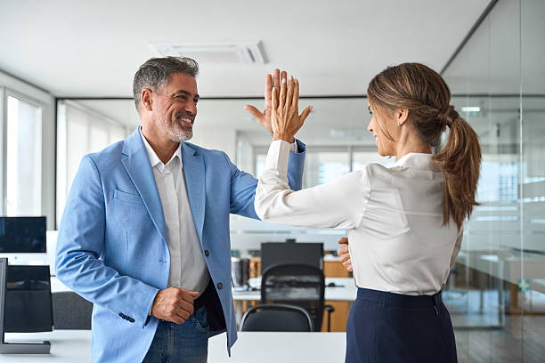 istock Happy business team two older executives giving high five at work in office. 2235903571