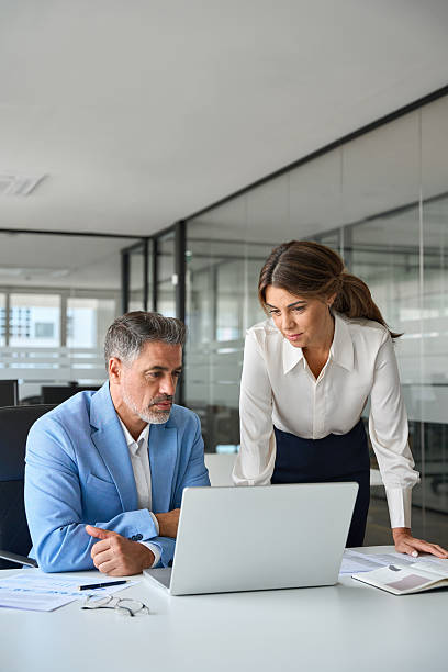 istock Two busy professional executives team working in office using laptop. Vertical 2235903709