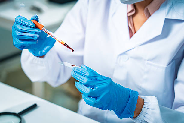 istock Female scientist in protective mask and gloves analyzing blood samples in test tubes inside a modern laboratory, symbolizing medical diagnostics, healthcare research, and scientific innovation. 2235903774