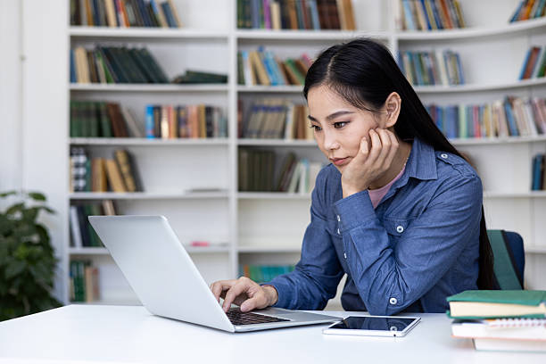 istock An Asian woman is concentrating while working on her laptop in a library. 2235907073