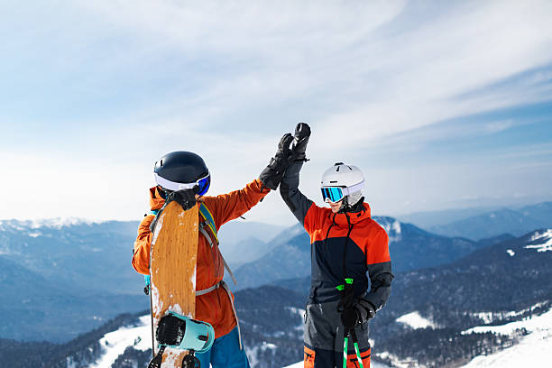Father and son skiing and snowboarding in mountain, giving hi-five