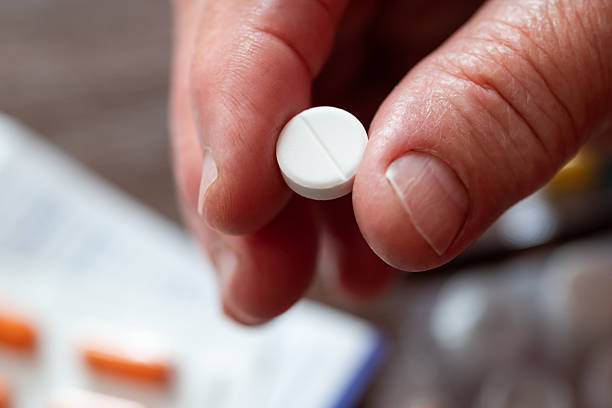 istock An elderly woman holding a white pill in her hand 2235909770