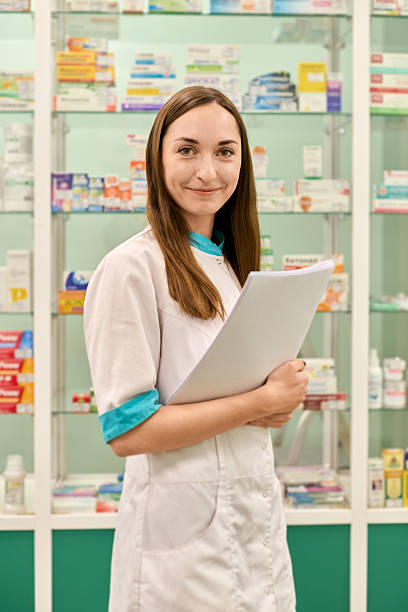 istock Young female pharmacist in pharmacy holding notebook 2235909919